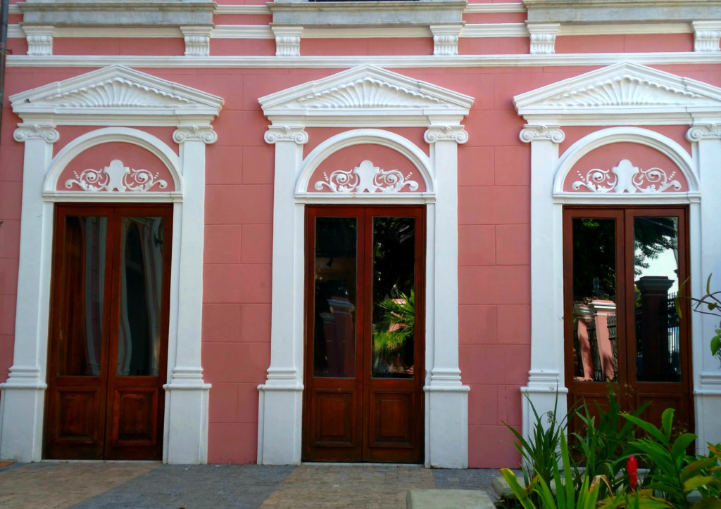 Detalhe de três portais brancos em contrates com a parede rosa.