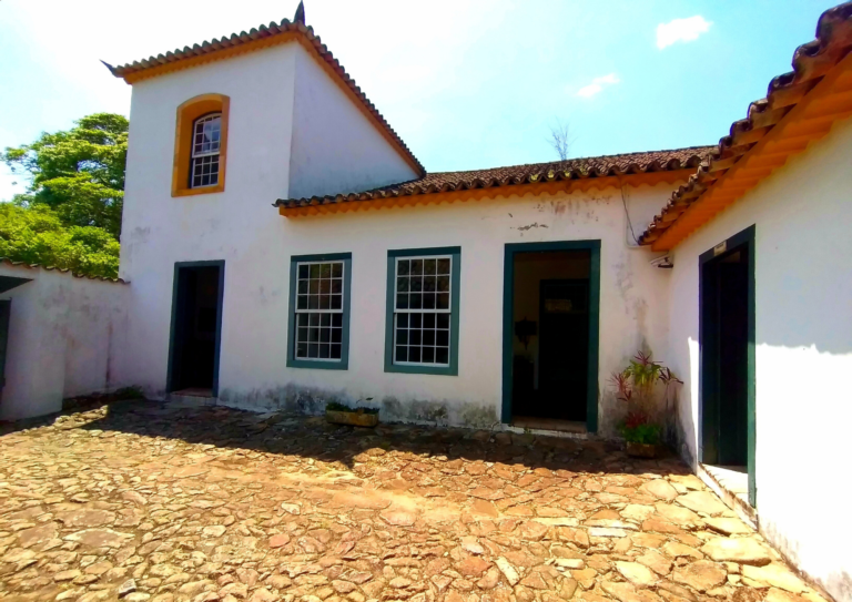 Pátio interno do museu que dava acesso ao casarão. O chão é de pedra e o sobrado tem paredes brancas, duas janelas no ´terreo e um no primeiro andar. Também tem duas portas no térreo.