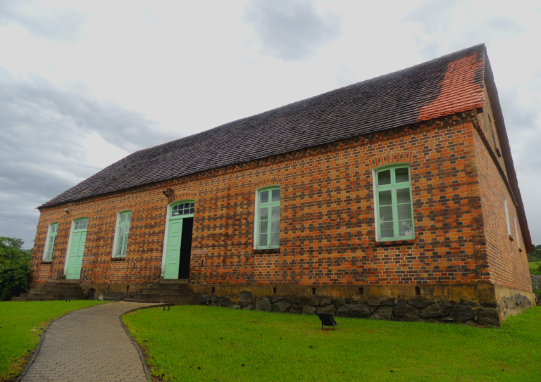 lateral Museu da música de Timbó, casa em tijolos com porta verde e 3 janelas